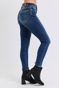 Judy Blue Mid Rise Thermal Skinny Jeans. Featuring Judy Blue stretch denim with a brushed thermal interior for an extra layer of warmth. Designed with a mid rise, dark wash, stitching on the back pockets, and no distressing.