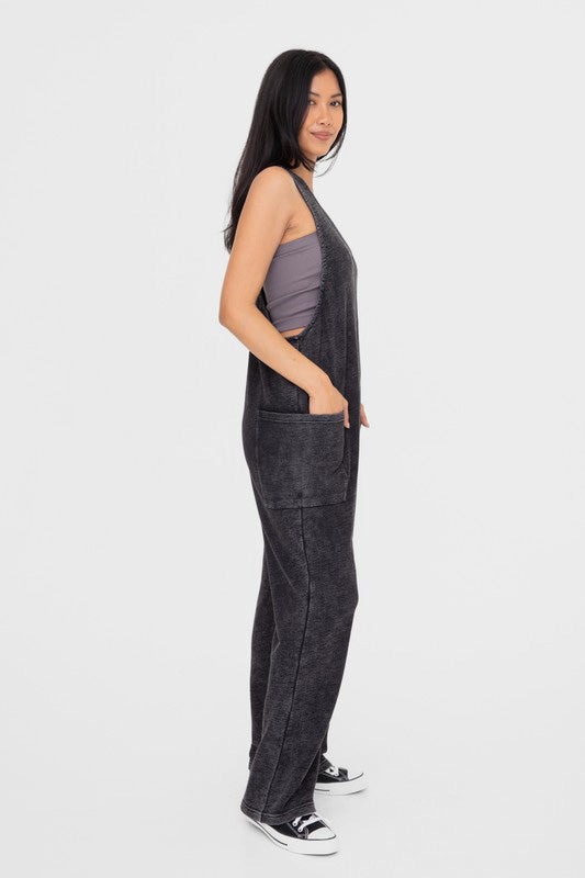 Balance Mineral Washed Lounge Jumpsuit. Mono B brand mineral washed jumpsuit features a soft cotton textured fabric with a vintage look, v neckline with wide straps that are joined with a center knot detail at the back, and finished with large patch pockets.