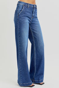 RISEN High Rise Wide Leg Slanted Pockets Jeans. Medium wash stretch denim designed with a high rise, wide leg silhouette, slanted front pockets, and finished with a trouser hem.