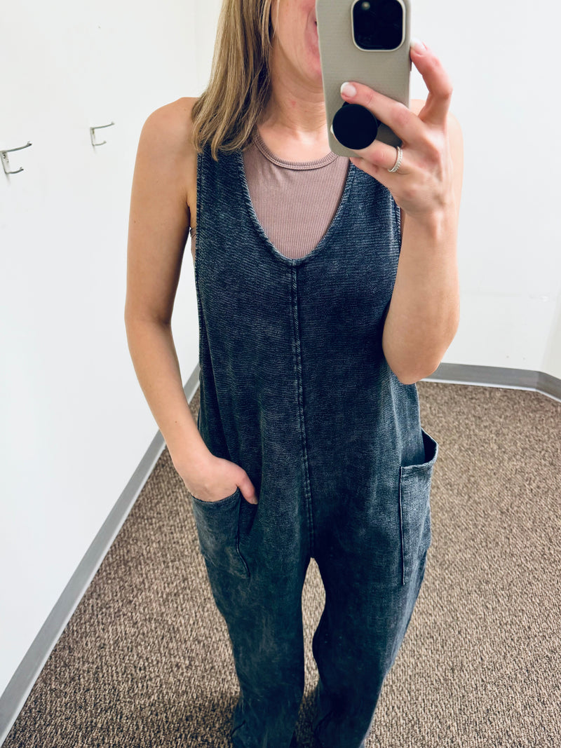 Balance Mineral Washed Lounge Jumpsuit. Mono B brand mineral washed jumpsuit features a soft cotton textured fabric with a vintage look, v neckline with wide straps that are joined with a center knot detail at the back, and finished with large patch pockets.