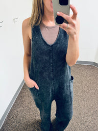 Balance Mineral Washed Lounge Jumpsuit. Mono B brand mineral washed jumpsuit features a soft cotton textured fabric with a vintage look, v neckline with wide straps that are joined with a center knot detail at the back, and finished with large patch pockets.