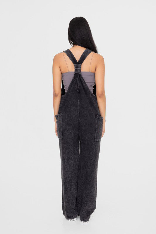 Balance Mineral Washed Lounge Jumpsuit. Mono B brand mineral washed jumpsuit features a soft cotton textured fabric with a vintage look, v neckline with wide straps that are joined with a center knot detail at the back, and finished with large patch pockets.