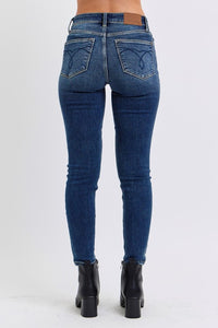 Judy Blue Mid Rise Thermal Skinny Jeans. Featuring Judy Blue stretch denim with a brushed thermal interior for an extra layer of warmth. Designed with a mid rise, dark wash, stitching on the back pockets, and no distressing. 