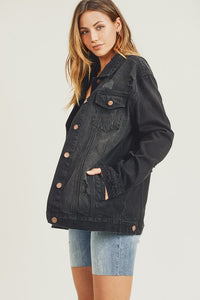 RISEN Black Vintage Wash Oversized Denim Jacket. Vintage wash black denim jacket with distressed details, button down front, button cuffs, front button pockets, additional side pockets, and a relaxed fit.